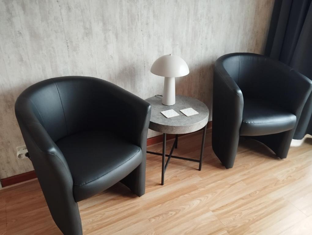 two black chairs and a table with a lamp at Logies Lily in Oudenburg