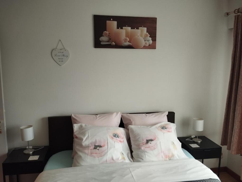 um quarto com uma cama com almofadas e duas mesas em Logies Lily em Oudenburg