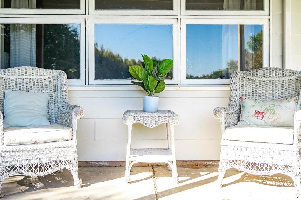 twee rieten stoelen en een tafel op een veranda bij Sea View Cottage Escape in Middleton