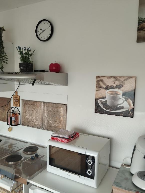 a kitchen with a microwave and a clock on the wall at Logies Lily in Oudenburg