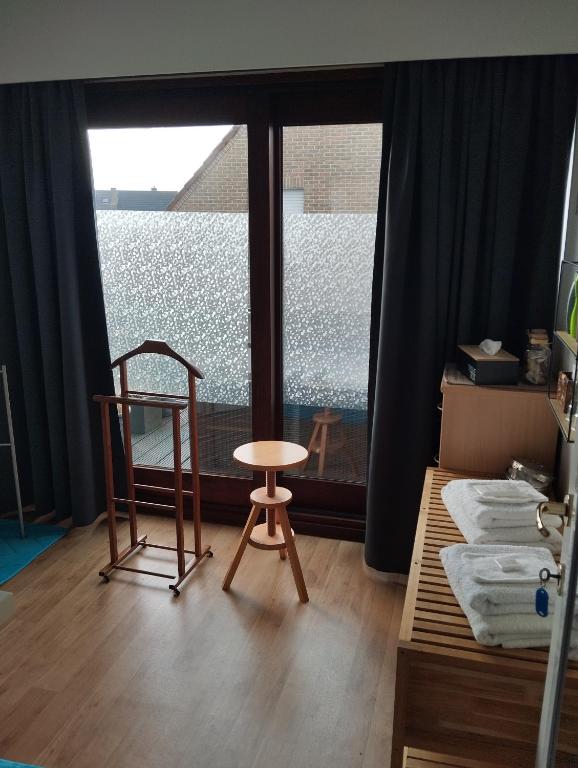 a room with a chair and a large window at Logies Lily in Oudenburg