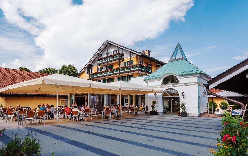 eine Gruppe von Personen, die außerhalb eines Gebäudes sitzen in der Unterkunft Schmelmer Hof Hotel & Resort in Bad Aibling