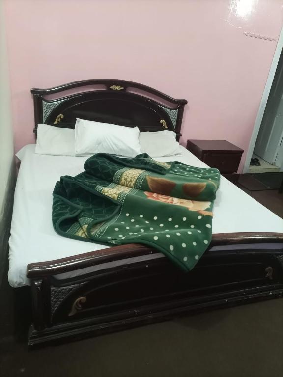 a bed with a green blanket and pillows on it at Kaghan Valley Hotel in Nārān