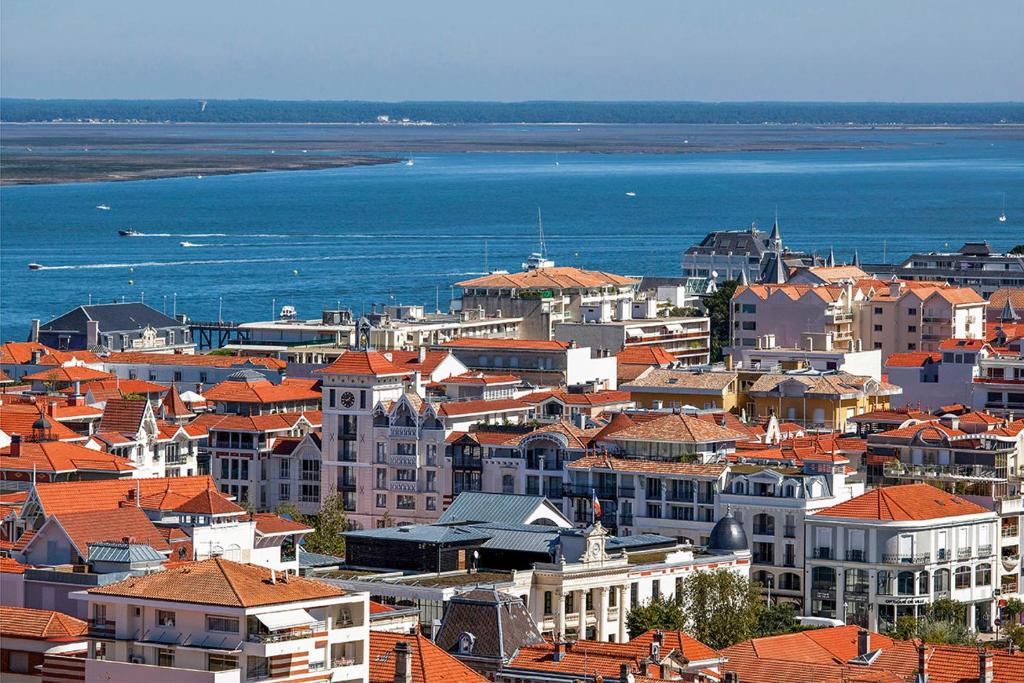 a group of buildings with orange roofs and the water at Rayon de soleil Arcachon in Arcachon