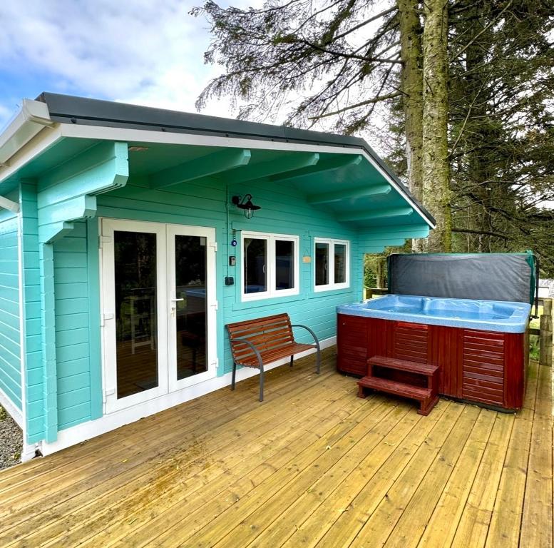 a blue tiny house with a bench on a deck at Glenariff Forest Larch Cabin in Glenariff