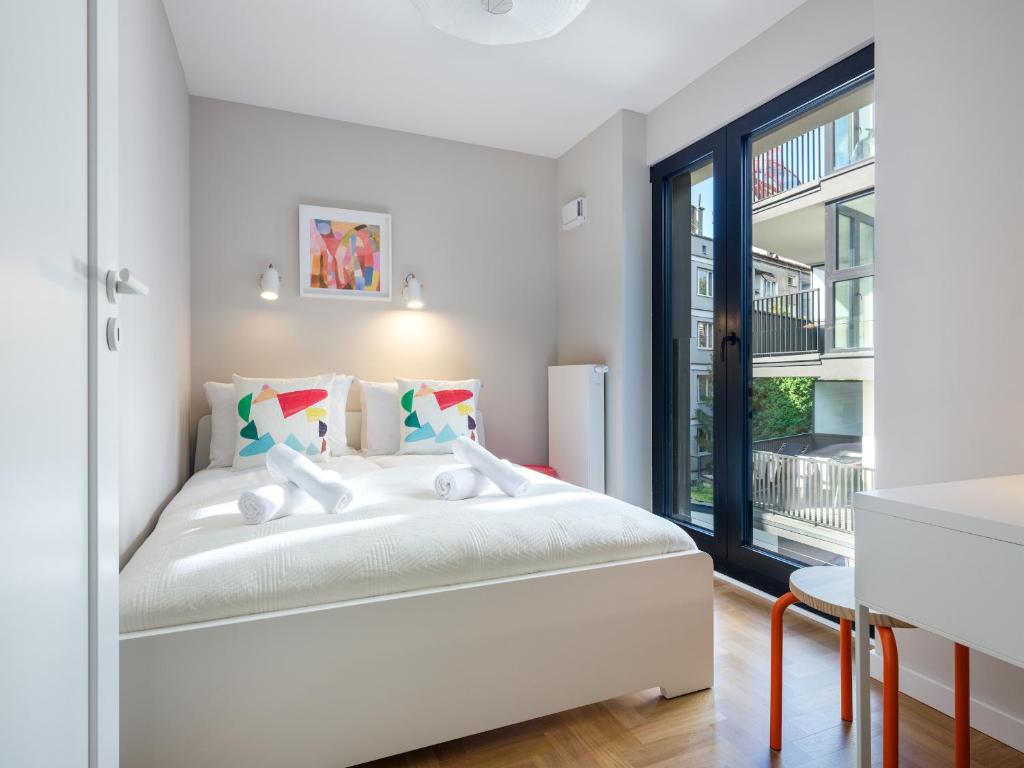 a white bedroom with a bed and a window at Tyzenhauz Apartments Vistula with Parking in Krakow