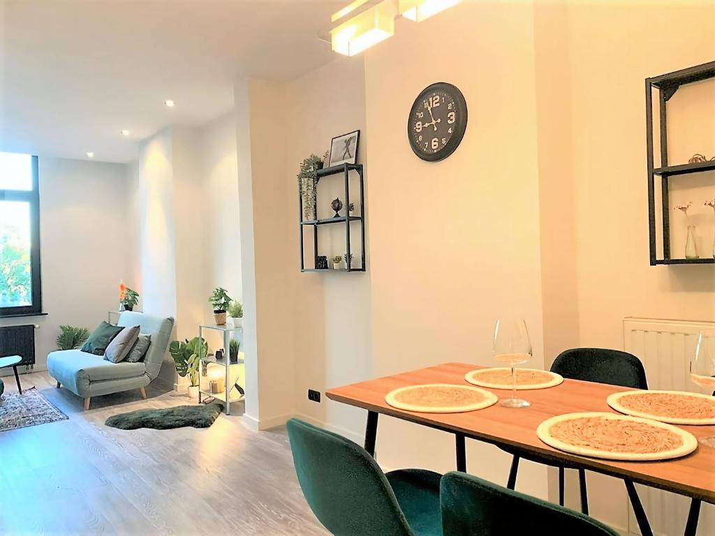 comedor con mesa, sillas y reloj en Royal South - Apartment Antwerp with Parkview en Amberes