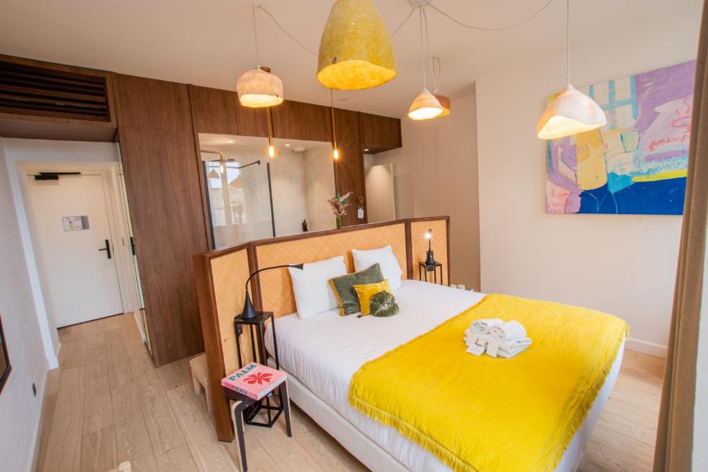 a bedroom with a large bed with a yellow blanket at LOLA Boutique Hôtel - Bordeaux Centre in Bordeaux