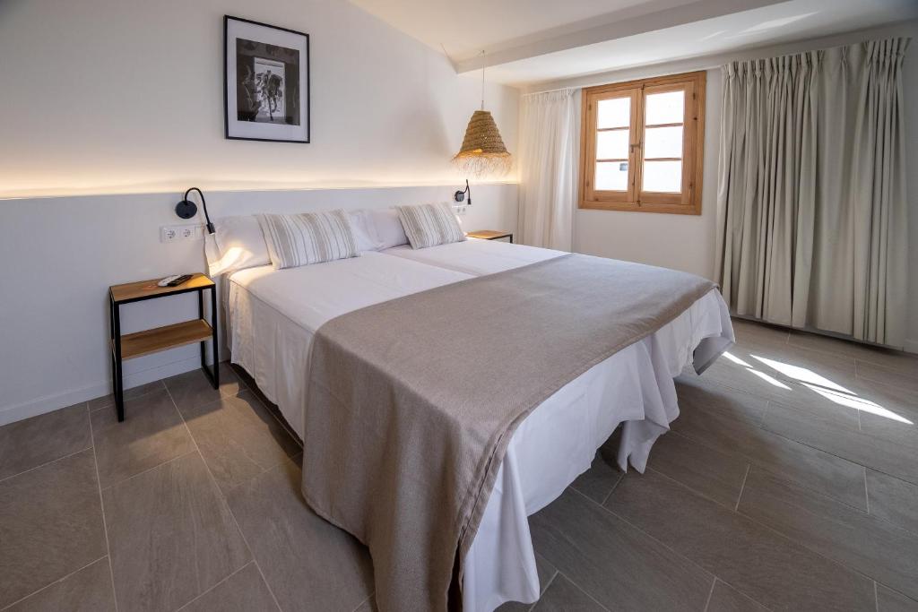 a bedroom with a large bed and a window at Tres Tocs in Ciutadella