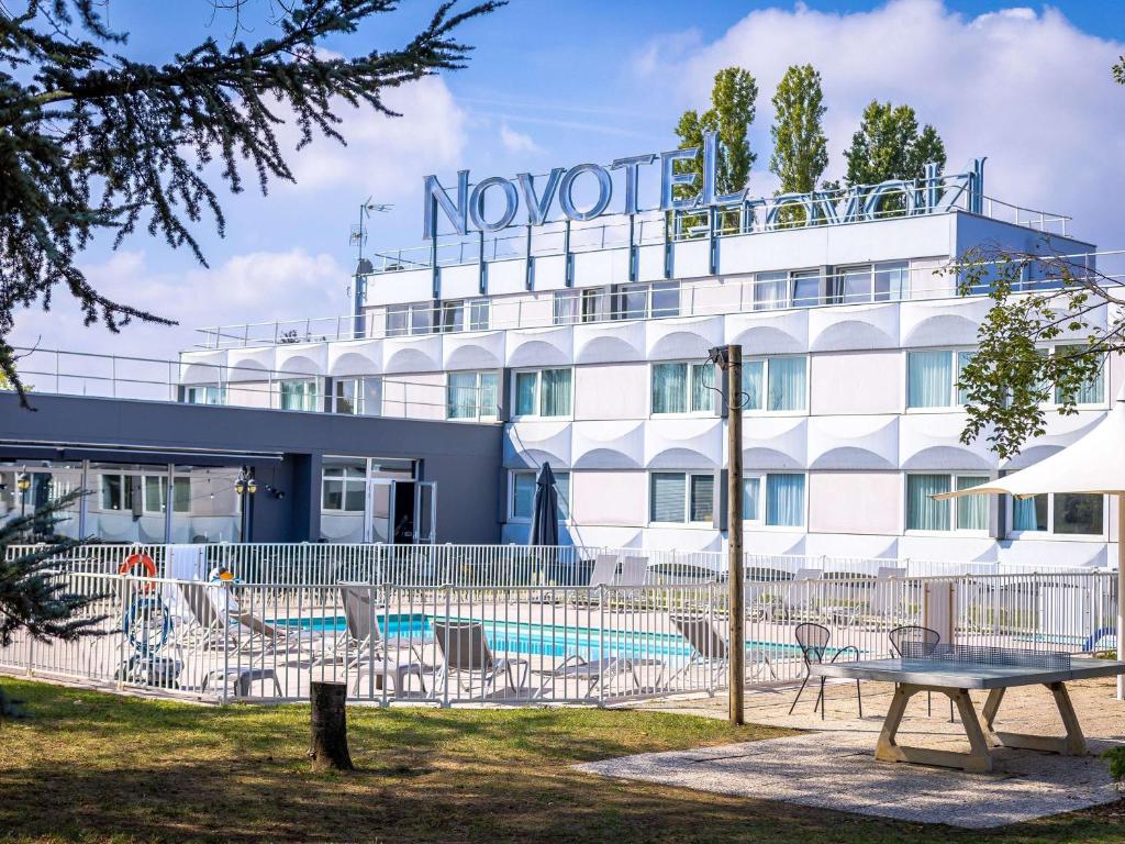 un hôtel avec une piscine en face d'un bâtiment dans l'établissement Novotel Mulhouse Bâle Fribourg, à Sausheim