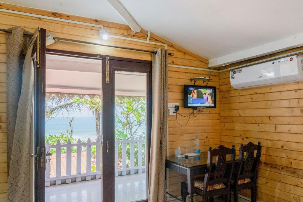 una puerta corredera de cristal que da a un balcón con mesa en Peles Windsong wooden cottages, en Benaulim