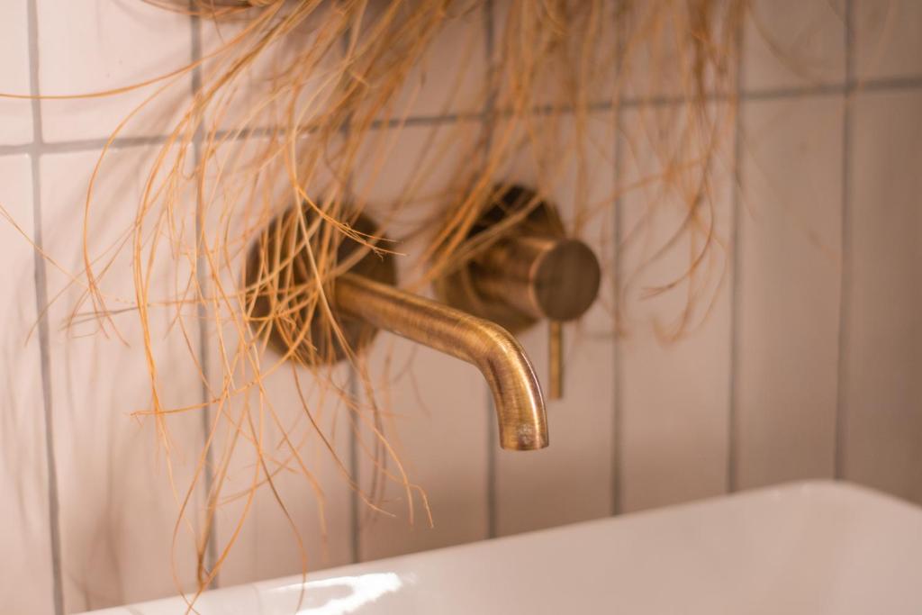 a close up of a bathroomaucet with hair hanging over a tub at LOLA Boutique Hôtel - Bordeaux Centre in Bordeaux