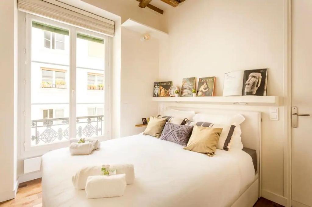 une chambre blanche avec un grand lit blanc et une fenêtre dans l'établissement Picasso, rue Debelleyme 4 places, à Paris