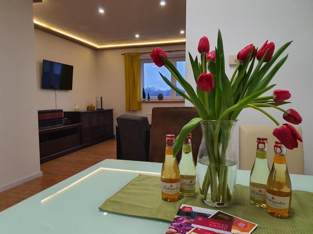 a table with a vase of flowers and bottles of beer at Ferienwohnung am Nationalpark Hunsrück Hochwald in Brücken