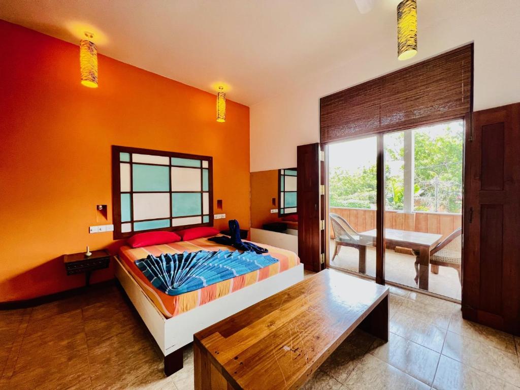 um quarto com paredes cor de laranja, uma cama e uma mesa em Gomez Place em Negombo