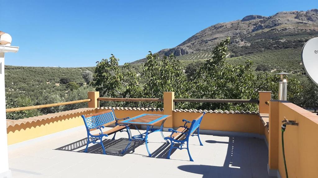 una mesa y sillas en un balcón con una montaña en Cortijo Ramonsillos en Villanueva del Trabuco