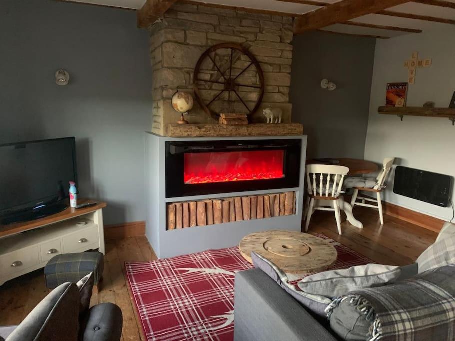 a living room with a fireplace with a red fire at Hays cottage in Halifax