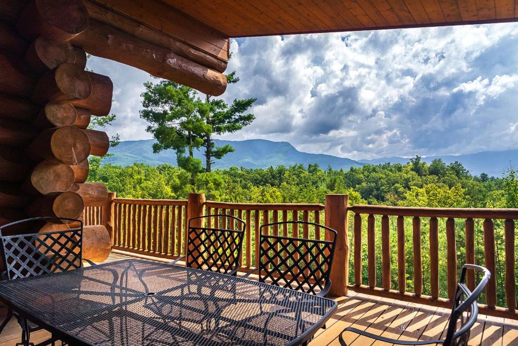 a table and chairs on a balcony with a view at Big Bear Ridge Lodge - Breathtaking mountain views and private forest scenes in amazing large log cabin in Gatlinburg