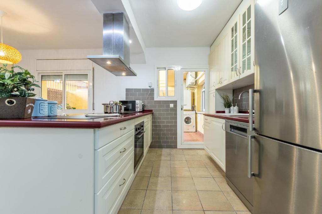 a kitchen with white cabinets and a stainless steel refrigerator at Pepe’s Apartment Salou in Salou