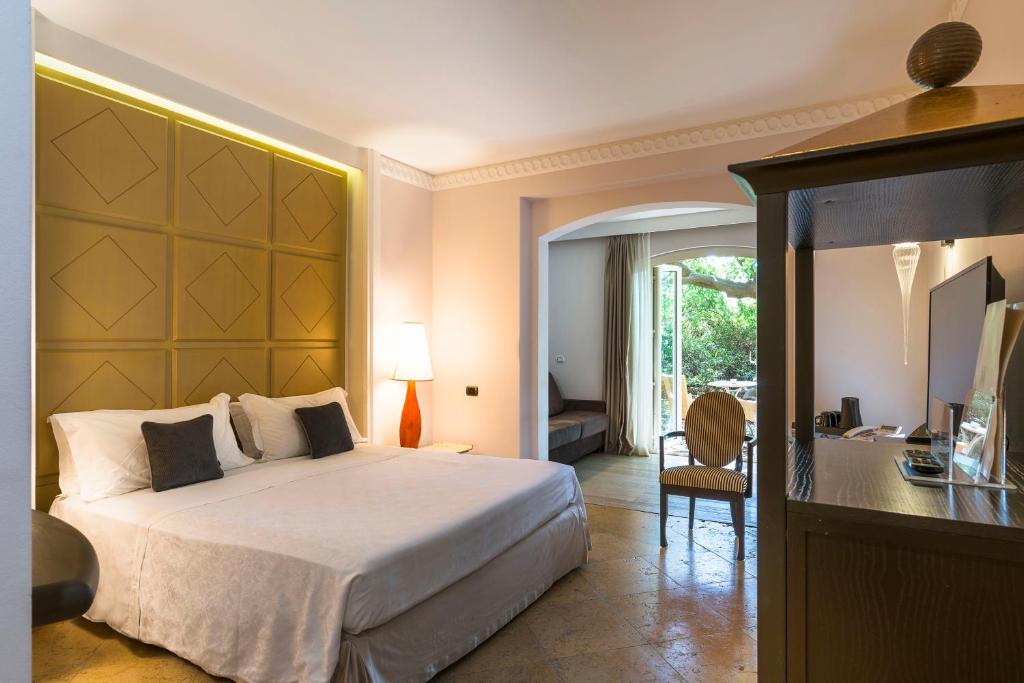 een slaapkamer met een groot bed en een bureau met een stoel bij Romano Palace Luxury Hotel in Catania