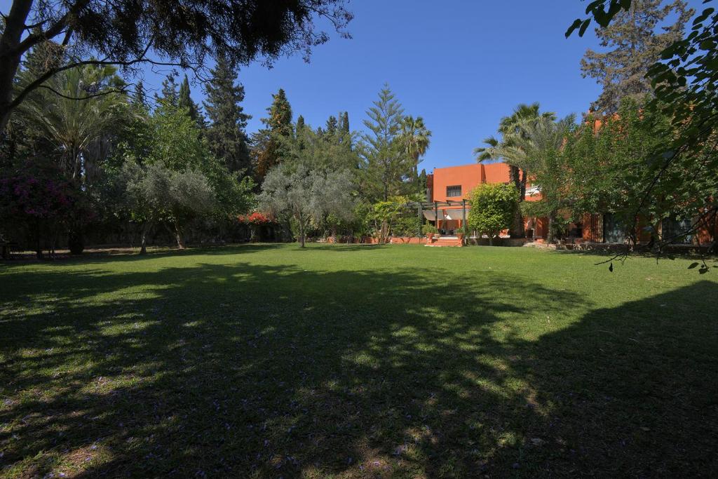 a large green field with trees and a building at Riad Raja in La Soukra
