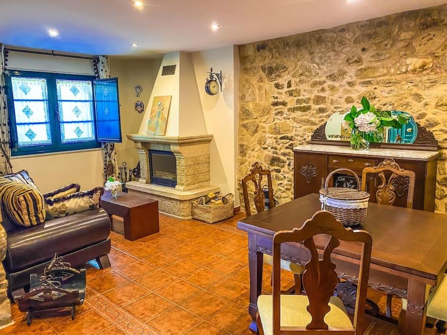 ein Wohnzimmer mit einem Tisch und einem Steinkamin in der Unterkunft Casa de Ina in Outes