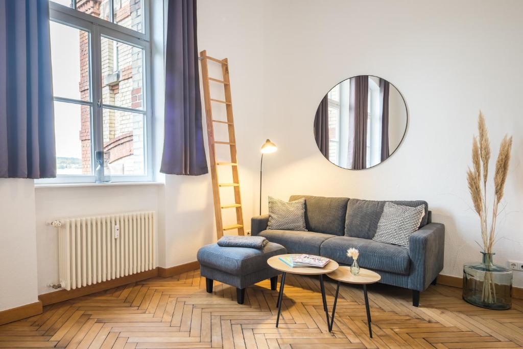 a living room with a couch and a table and a mirror at SCHWARZLINS LoftRaum - Stilvolles Apartment mit Smart TV, NETFLIX, Disney Plus, schnellem WLAN, Parken, Nespresso in Sankt Ingbert