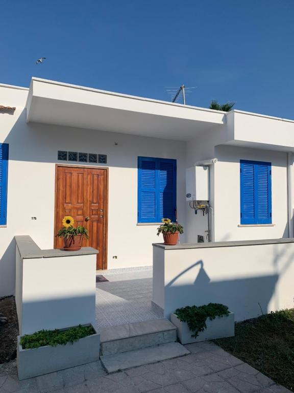 Una casa blanca con persianas azules. en La Casetta sul mare - Alloggio turistico en Fiumicino