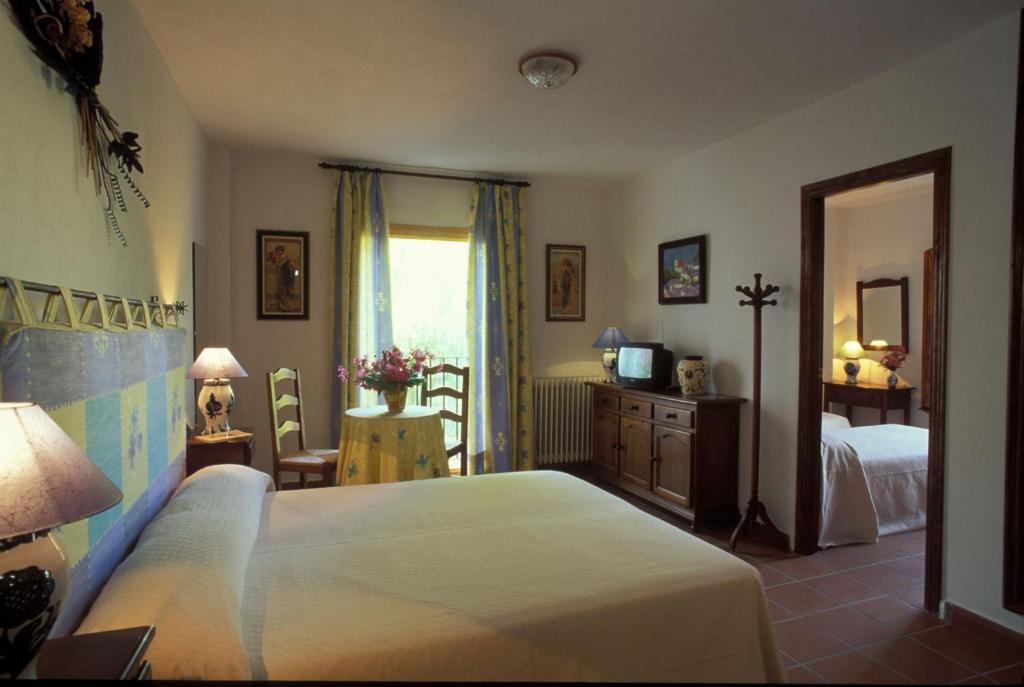 a bedroom with a bed and a television and a window at Hotel De Mecina Fondales in Mecina Fondales