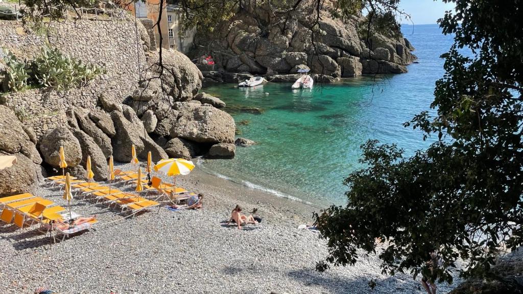 a beach with chairs and umbrellas and people in the water at Casa dell'Arco 31 in Camogli