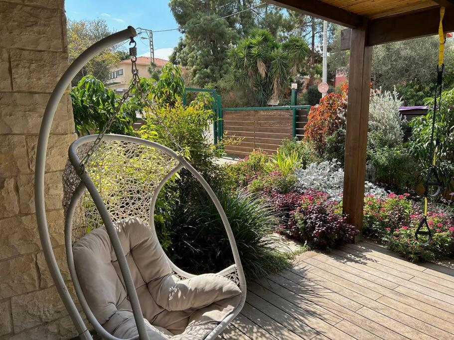 a wicker chair sitting on a patio with a garden at In the center of the Moshava in Zikhron Ya‘aqov
