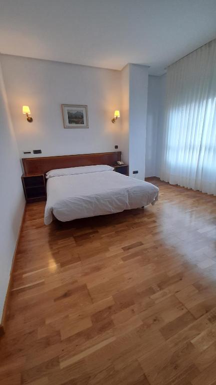 Hotel Las Moreras في ليون: غرفة نوم بسرير وارضية خشبية