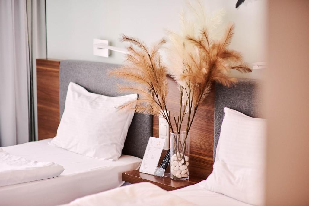a bedroom with two beds and a vase with feathers at Focus Hotel Premium Lublin Conference & SPA in Lublin