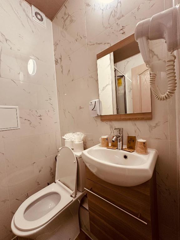 a white bathroom with a toilet and a sink at Pavillon Opéra Lafayette in Paris