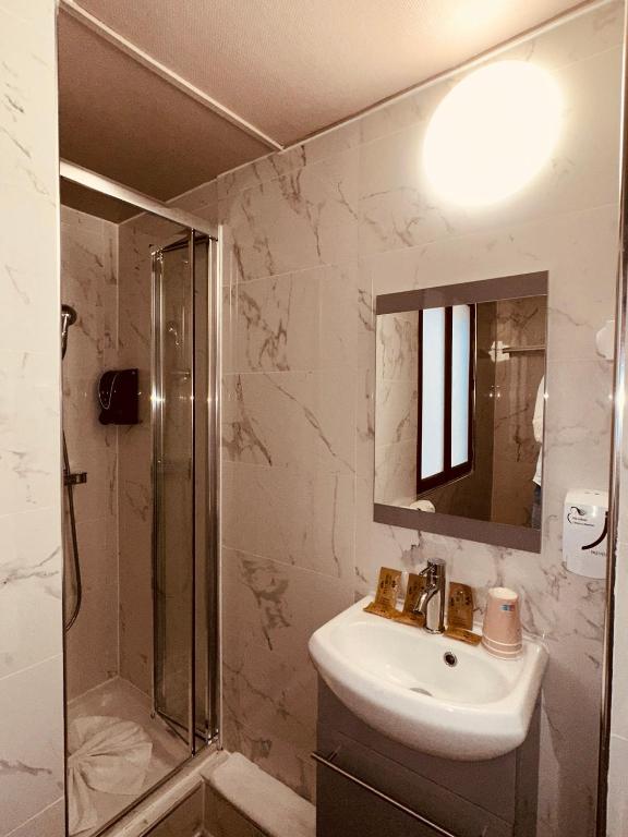 a bathroom with a sink and a shower and a mirror at Pavillon Opéra Lafayette in Paris