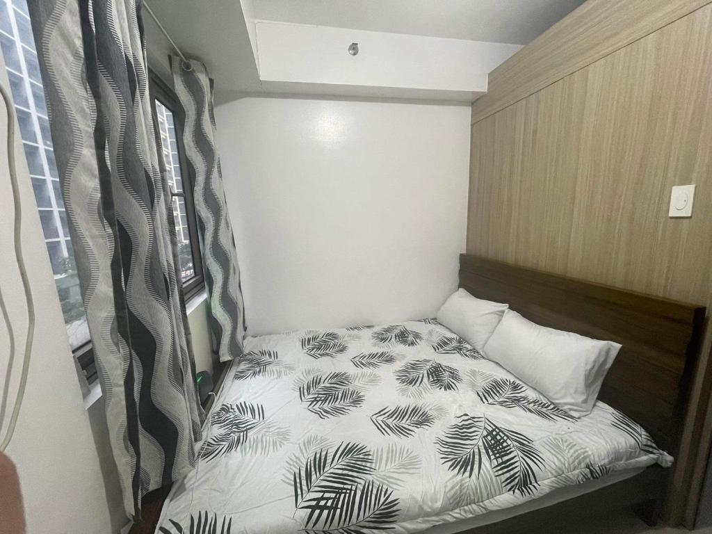 Ce petit lit se trouve dans une petite chambre dotée d'un canapé-lit. dans l'établissement Shore residences Ph, à Manille