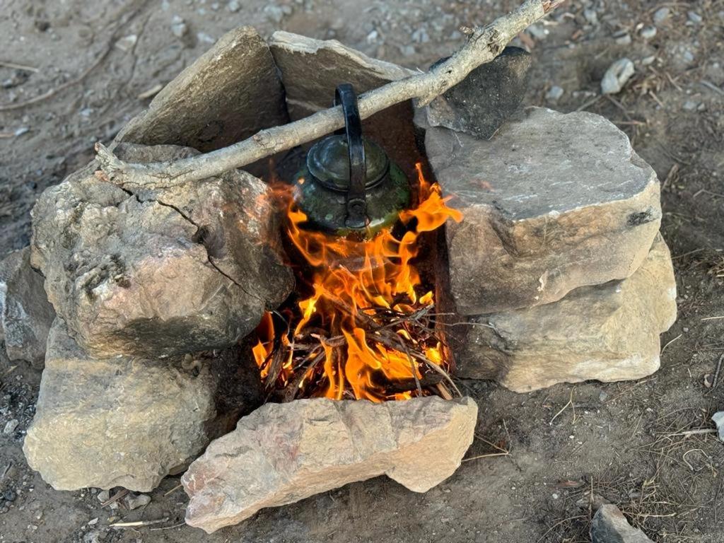 a fire pit with a pot on top of some rocks at 7 Caves Hotel in Al Jāyah