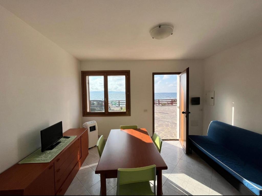 sala de estar con sofá y mesa con sillas en ~ Green House sul Mare ~, en Calasetta