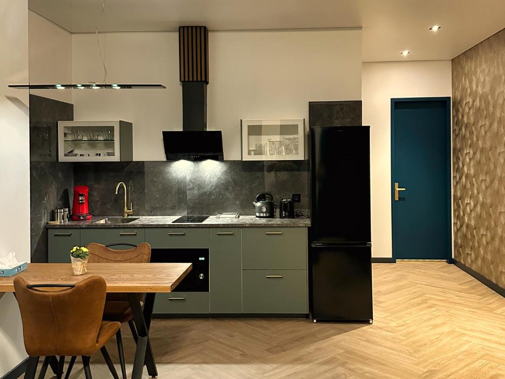 a kitchen with a table and a black refrigerator at Luxe appartement dichtbij centrum Drachten in Drachten