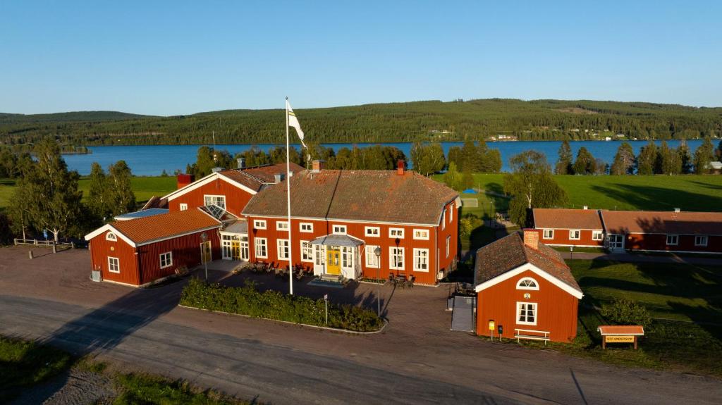 an aerial view of a large red house with a lake at STF Undersvik Gårdshotell & Vandrarhem in Vallsta