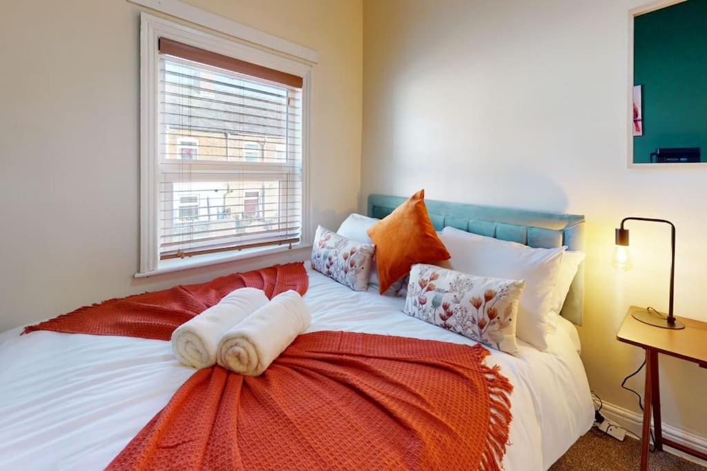a bedroom with a bed with pillows and a window at Cosy 3 bedroom home from home in Lostock Gralam