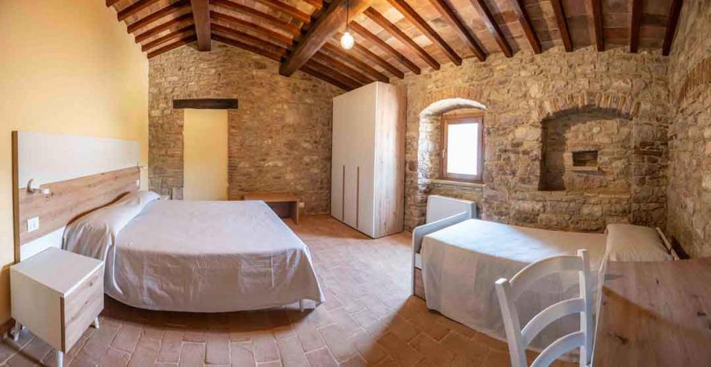 a bedroom with two beds and a stone wall at Abbazia San Pietro in Valle in Vagli