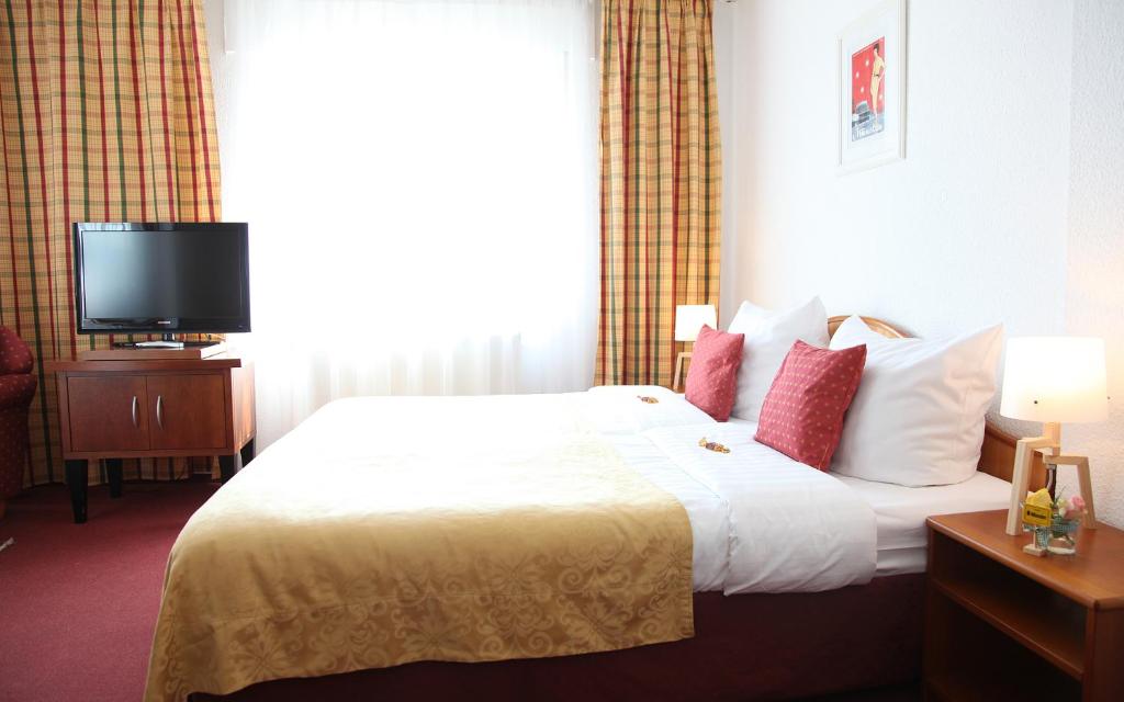 a hotel room with a bed and a television at Cityhotel Amadeus in Münster