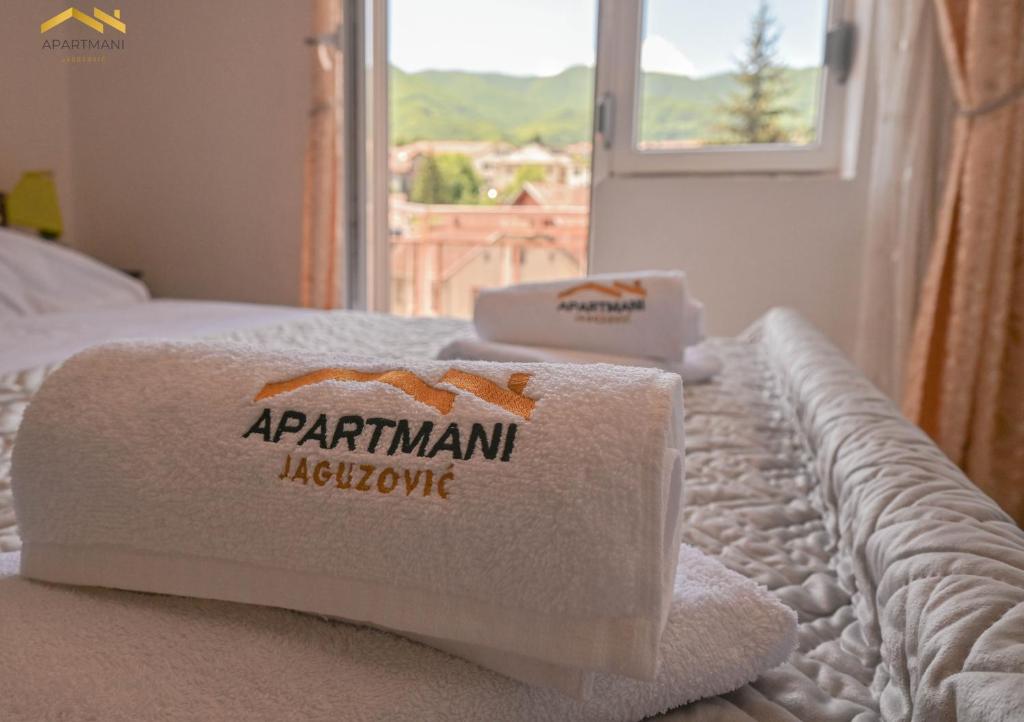 a pile of towels on a bed with a window at Apartmani Jaguzovic in Mrkonjić Grad