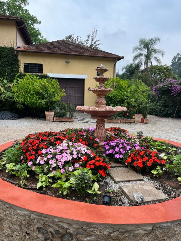 a flower garden with a fountain in front of a house at Vila Adega Maravilha in São Roque