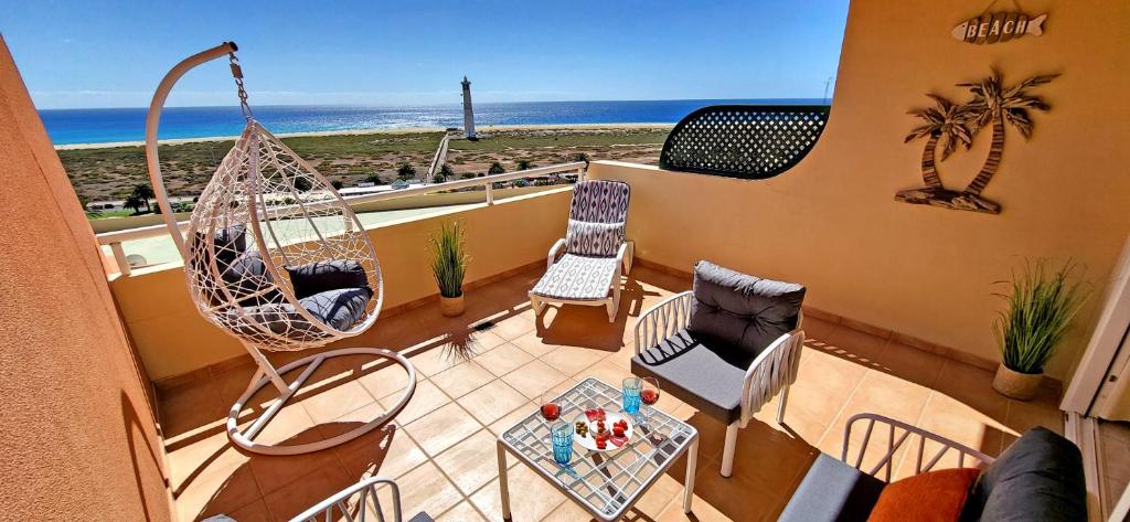 - un balcon avec une balançoire, des chaises et la plage dans l'établissement Ferienwohnung Jandia Dream, à Morro del Jable