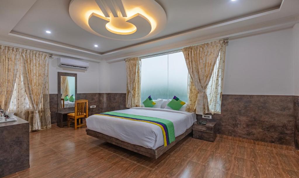 Schlafzimmer mit einem großen Bett und einem Deckenventilator in der Unterkunft Treebo Trend Siri Ambari Resorts in Madikeri