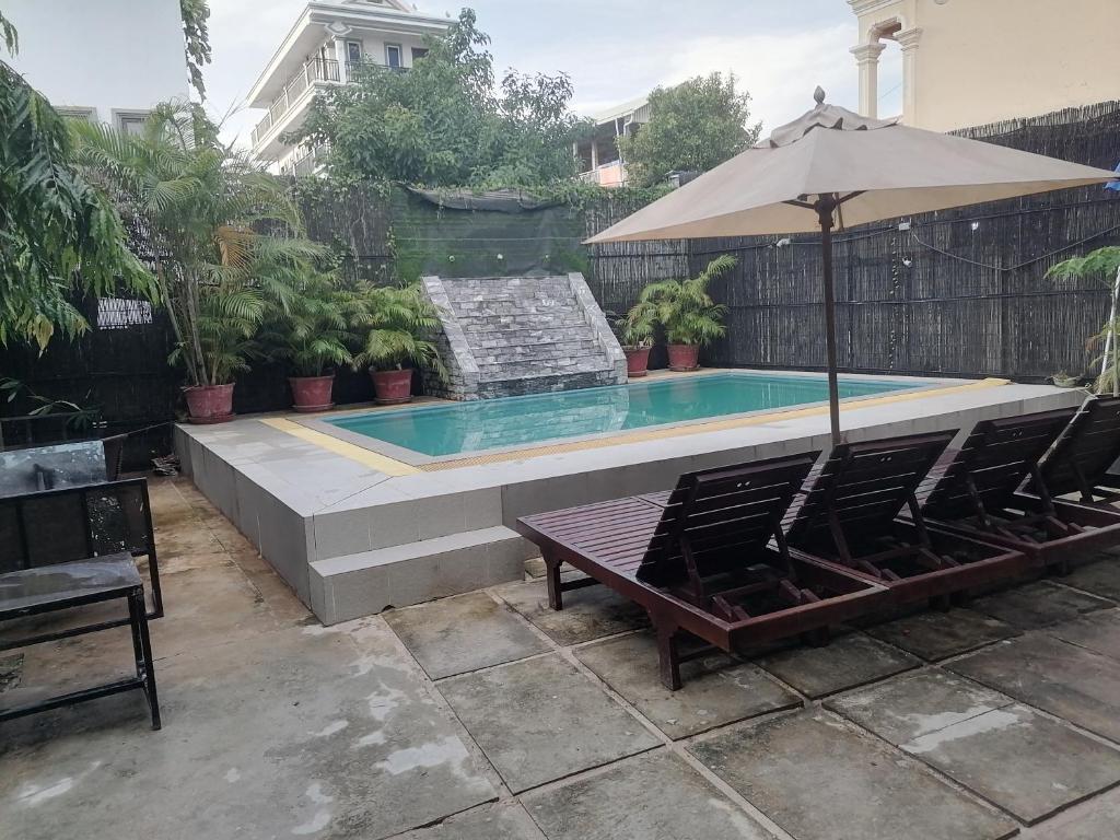 a swimming pool with two chairs and an umbrella at Jack's Guesthouse in Siem Reap