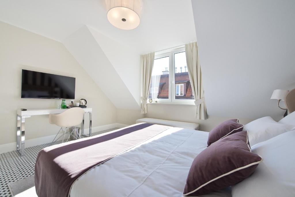 a white bedroom with a bed and a desk at Monte Cassino in Sopot