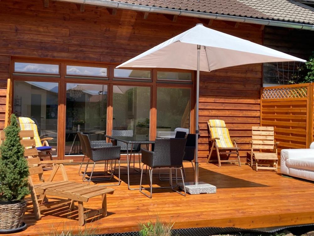 une terrasse avec une table, des chaises et un parasol dans l'établissement Tu Casa Chiemsee, à Gstadt am Chiemsee